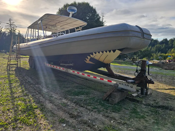 Ocean Spirit Yacht Photos Pics 1996 Eduardono RIB boat on trailer, featuring shark mouth design, parked outdoors.
