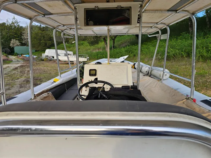 Ocean Spirit Yacht Photos Pics 1996 Eduardono RIB boat interior with steering wheel, canopy, and seating, set in a grassy area.