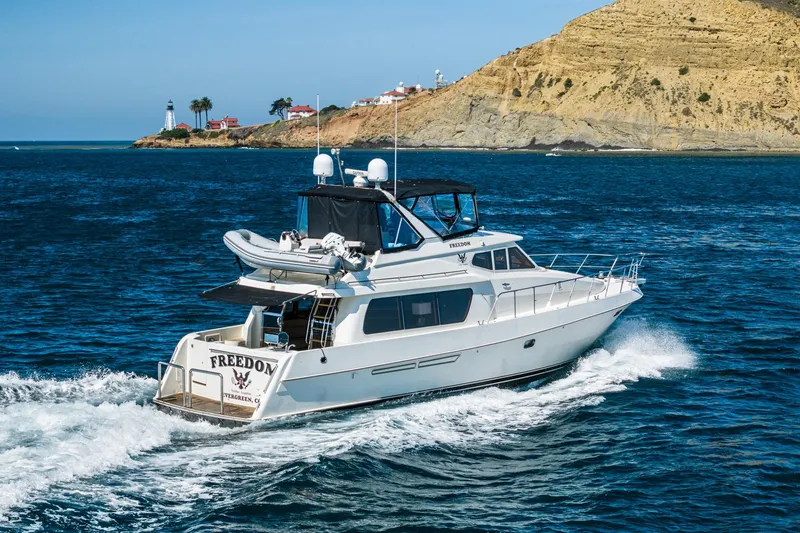 Freedom Yacht Photos Pics 2002 McKinna 57 Pilothouse yacht cruising near a scenic coastal lighthouse.