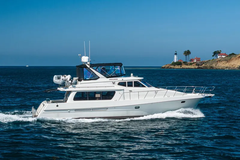 Freedom Yacht Photos Pics 2002 McKinna 57 Pilothouse yacht cruising near a scenic coastal lighthouse.