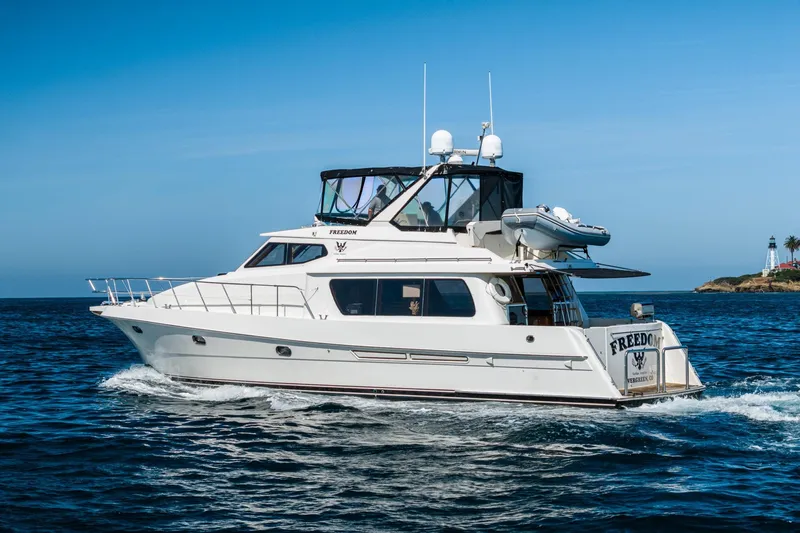 Freedom Yacht Photos Pics 2002 McKinna 57 Pilothouse yacht cruising on open water near a lighthouse.