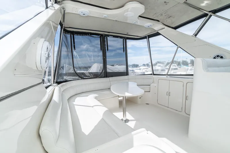 Freedom Yacht Photos Pics Luxurious interior of a 2002 McKinna 57 Pilothouse yacht with white seating and panoramic windows.