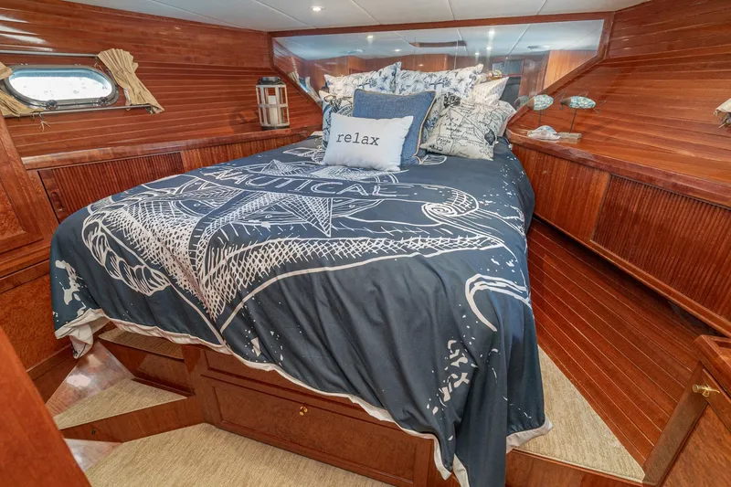 Freedom Yacht Photos Pics Luxurious 2002 McKinna 57 Pilothouse bedroom with nautical-themed bedding and wooden interior.