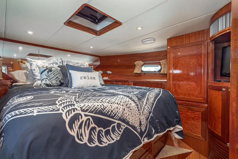 Freedom Yacht Photos Pics Luxurious 2002 McKinna 57 Pilothouse bedroom with elegant wood finish and nautical-themed bedding.