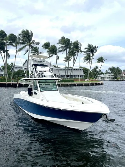 Reel Time Yacht Photos Pics 2013 Boston Whaler 370 Outrage boat on water, palm trees in background.