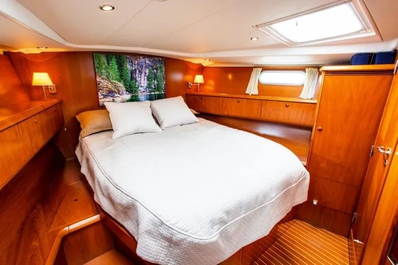 Rum Runner Yacht Photos Pics Luxurious cabin interior of 2007 Jeanneau Sun Odyssey 54 DS yacht, featuring cozy bed and wooden decor.