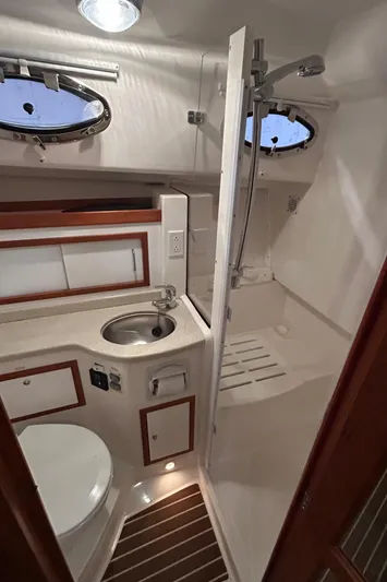  Yacht Photos Pics 2015 Back Cove 34 yacht bathroom with sink, toilet, and shower, featuring wooden accents and porthole windows.