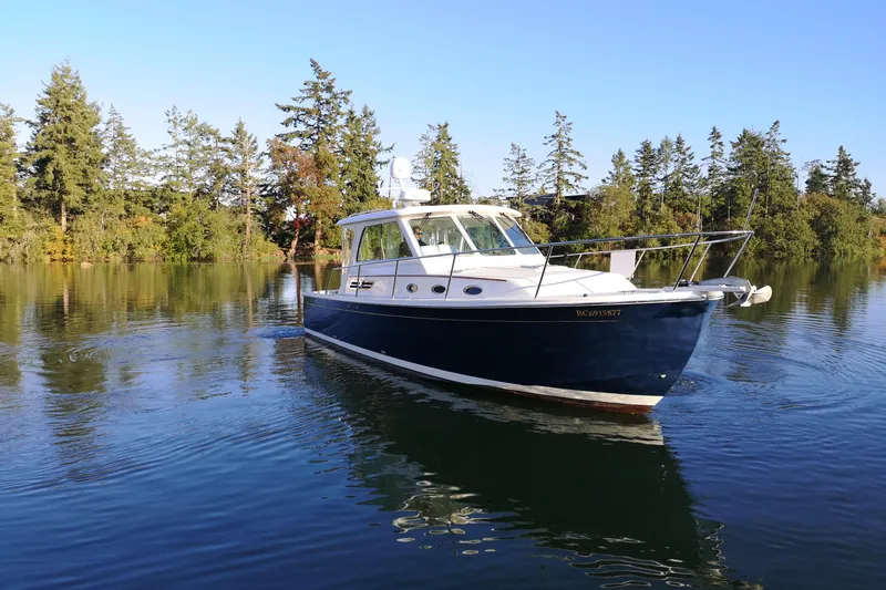  Yacht Photos Pics 2015 Back Cove 34 boat cruising on a serene lake surrounded by trees.