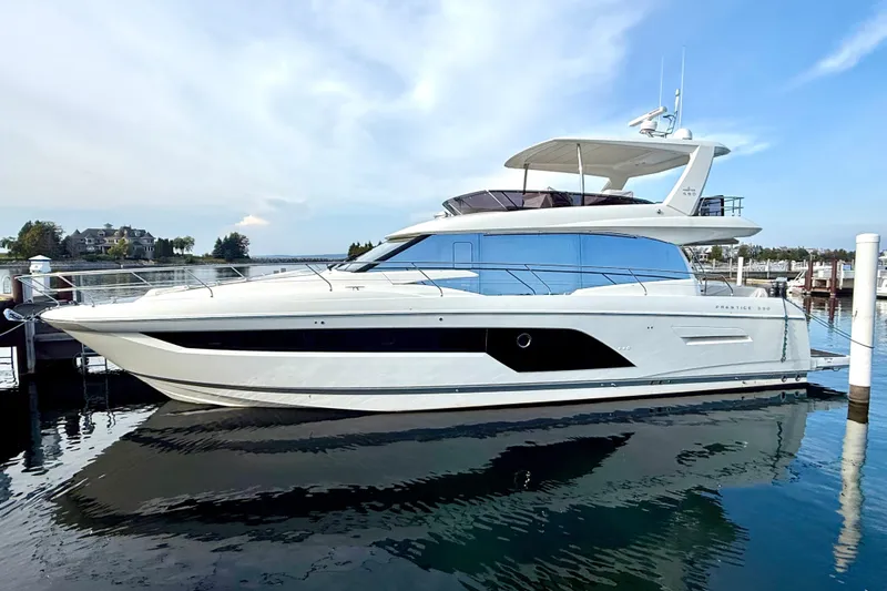 Freiheit Yacht Photos Pics Luxury 2020 Prestige 590 yacht docked at marina, reflecting on calm water.