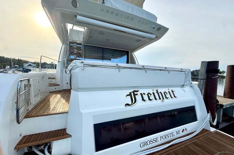 Freiheit Yacht Photos Pics Luxury 2020 Prestige 590 yacht docked, featuring elegant wooden deck and "Freiheit" nameplate.