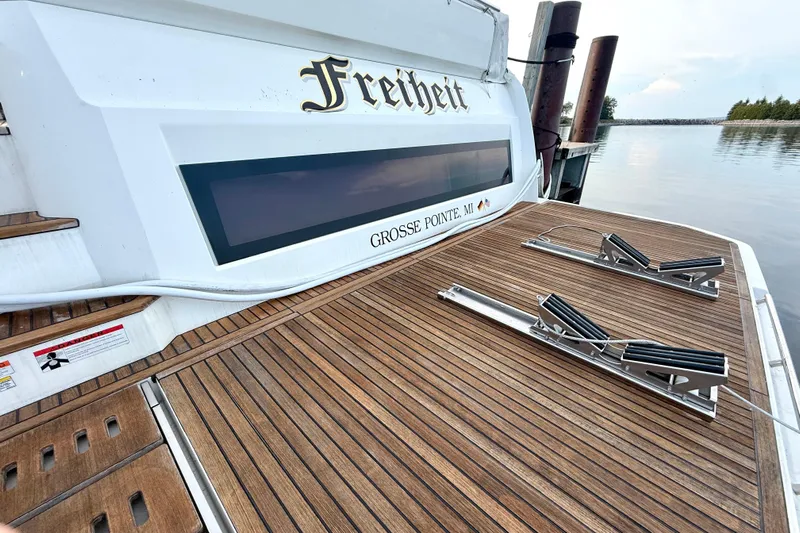 Freiheit Yacht Photos Pics Luxury 2020 Prestige 590 yacht with wooden deck, docked at serene waterfront.