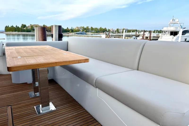 Freiheit Yacht Photos Pics Luxury seating area on 2020 Prestige 590 yacht with wooden table and waterfront view.