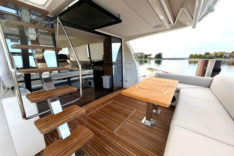 Freiheit Yacht Photos Pics Luxurious 2020 Prestige 590 yacht interior with wooden deck, seating, and scenic water view.