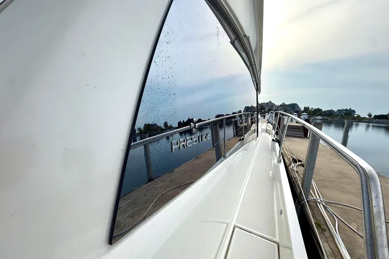 Freiheit Yacht Photos Pics 2020 Prestige 590 yacht docked, reflecting water and sky on its sleek exterior.