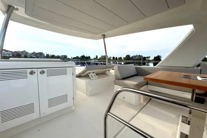 Freiheit Yacht Photos Pics Luxurious 2020 Prestige 590 yacht interior with seating and table, overlooking serene waterfront.