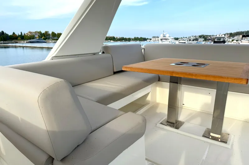 Freiheit Yacht Photos Pics Luxurious seating area on 2020 Prestige 590 yacht with wooden table, docked at marina.