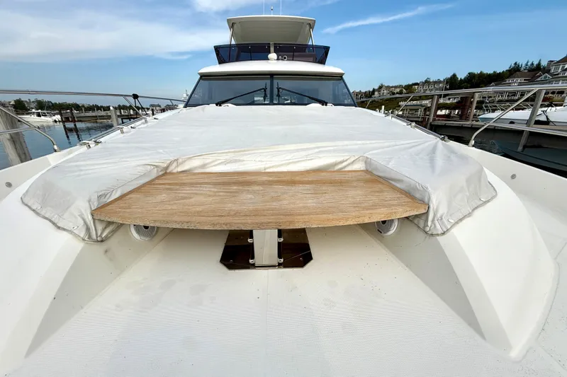 Freiheit Yacht Photos Pics 2020 Prestige 590 yacht deck with covered seating area and wooden table.