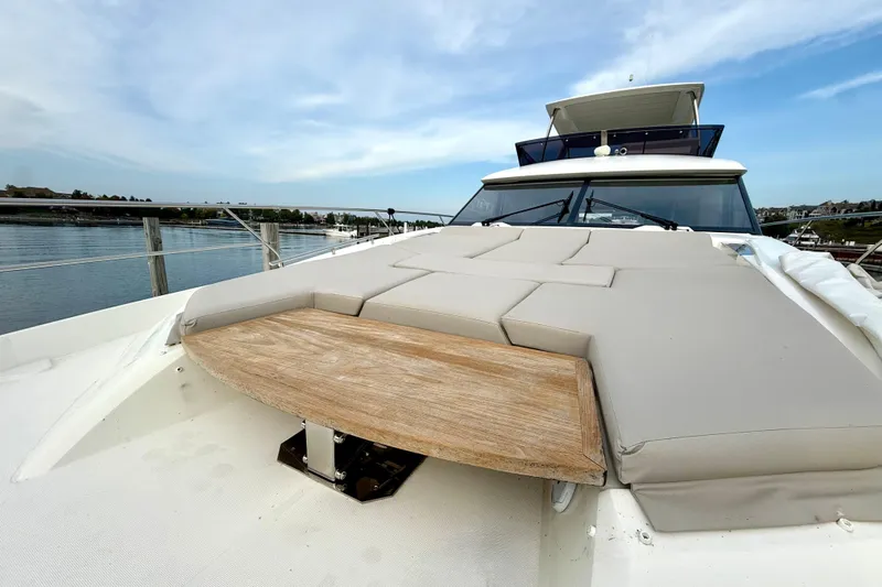 Freiheit Yacht Photos Pics Prestige 590 yacht 2020 model with cushioned deck and wooden table, docked by the water.