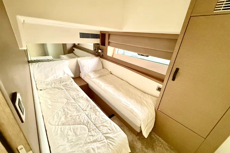 Freiheit Yacht Photos Pics Luxurious twin cabin interior of 2020 Prestige 590 yacht, featuring modern design and cozy bedding.