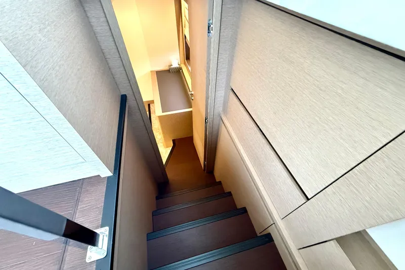 Freiheit Yacht Photos Pics Narrow staircase inside 2020 Prestige 590 yacht, featuring modern wood paneling and sleek design.