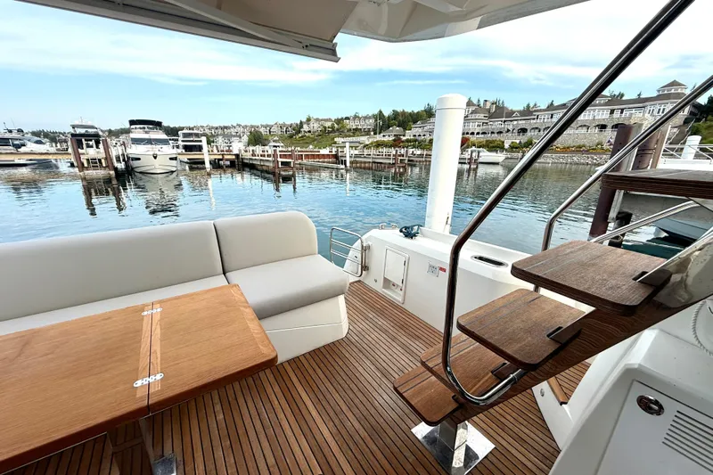 Freiheit Yacht Photos Pics Luxurious 2020 Prestige 590 yacht deck with seating, table, and marina view.