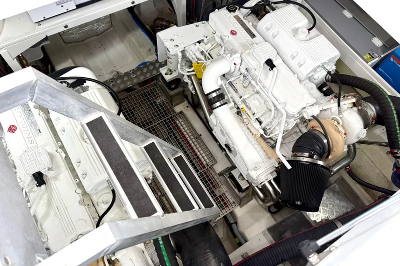 Freiheit Yacht Photos Pics Engine room of a 2020 Prestige 590 yacht, showcasing dual white engines and metal stairs.