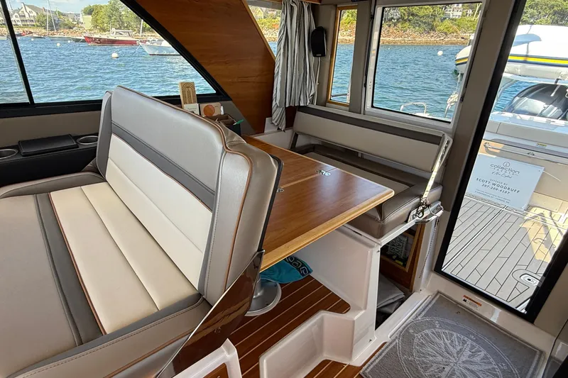 Frisky Yacht Photos Pics Interior of 2022 Cutwater C-32 CB boat with seating and table, overlooking water.