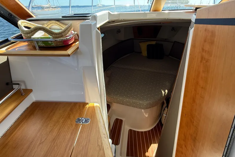 Frisky Yacht Photos Pics 2022 Cutwater C-32 CB cabin interior with wooden finishes and cozy bed.