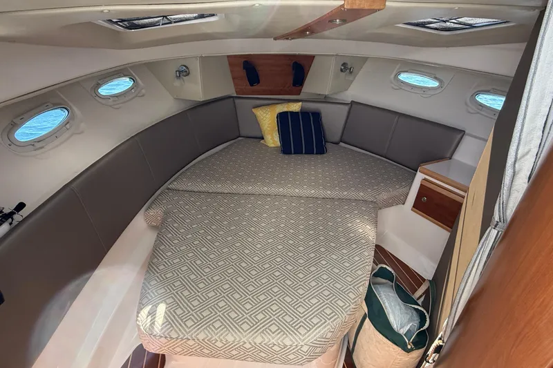 Frisky Yacht Photos Pics 2022 Cutwater C-32 CB cabin interior with bed, cushions, and portholes.