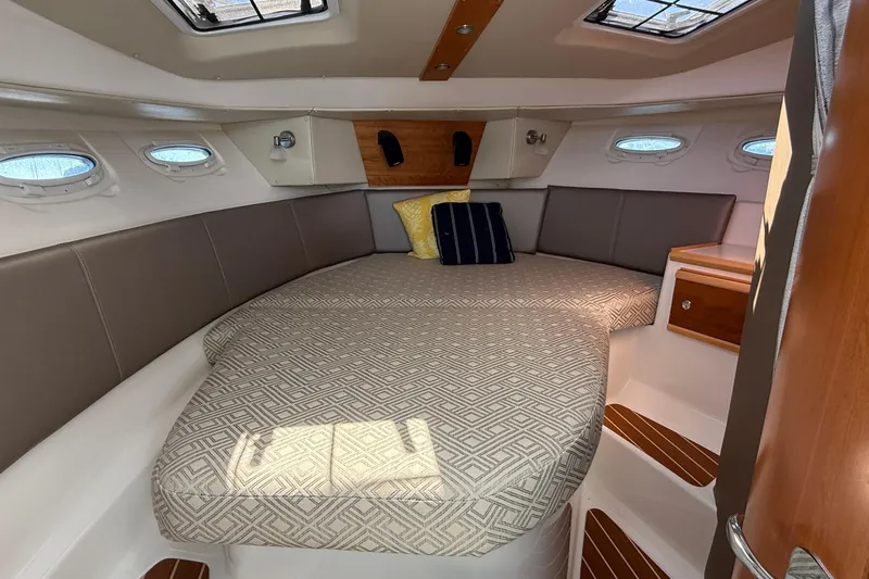 Frisky Yacht Photos Pics 2022 Cutwater C-32 CB cabin interior with cozy bed and porthole windows.