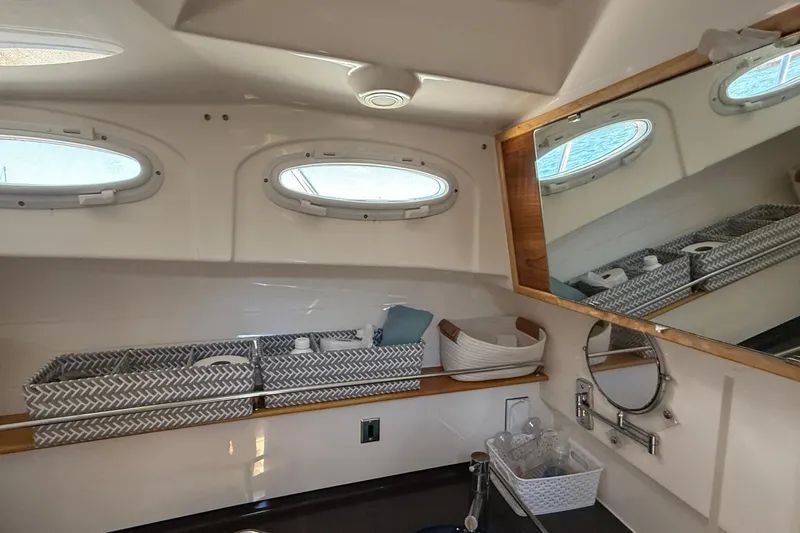 Frisky Yacht Photos Pics 2022 Cutwater C-32 CB boat bathroom with storage baskets, mirror, and porthole windows.