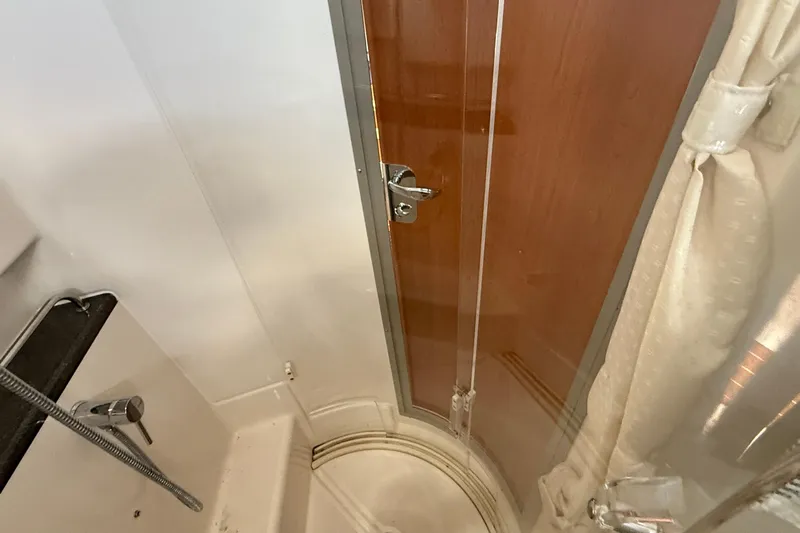 Frisky Yacht Photos Pics 2022 Cutwater C-32 CB boat interior shower with wooden door and chrome fixtures.