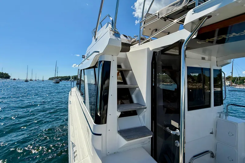 Frisky Yacht Photos Pics 2022 Cutwater C-32 CB boat on water, featuring exterior stairs and open cabin door.