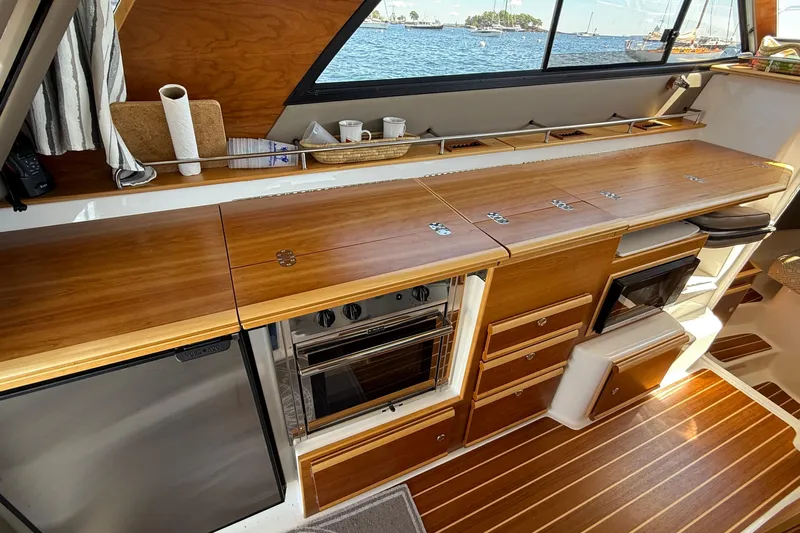 Frisky Yacht Photos Pics 2022 Cutwater C-32 CB yacht interior with wooden cabinetry and modern appliances.