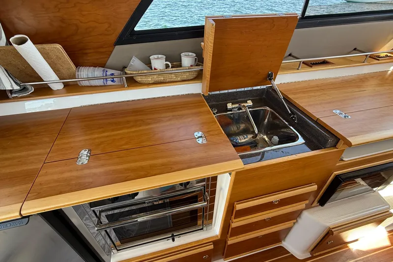 Frisky Yacht Photos Pics 2022 Cutwater C-32 CB yacht kitchen with wooden cabinetry and stainless steel sink.