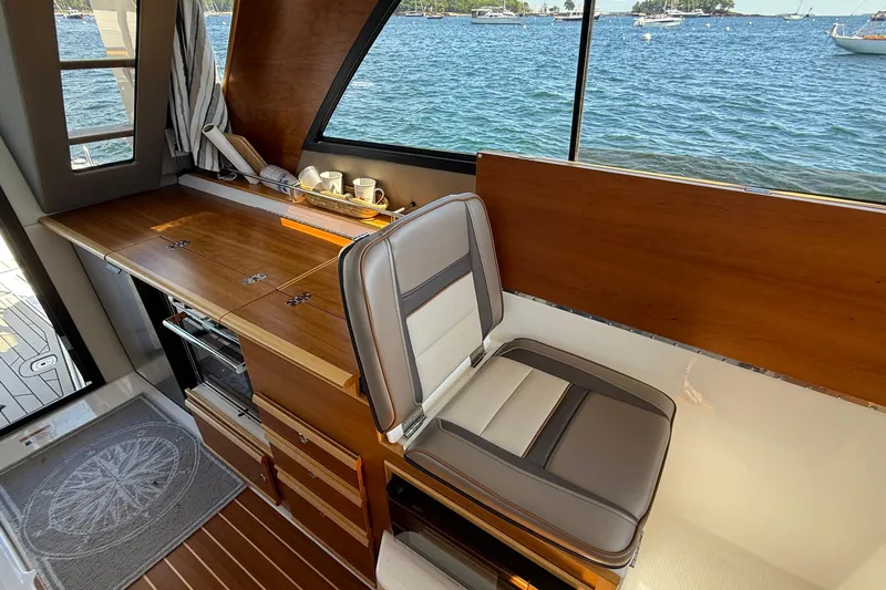 Frisky Yacht Photos Pics Interior of 2022 Cutwater C-32 CB boat with seating and wooden cabinetry by the window.