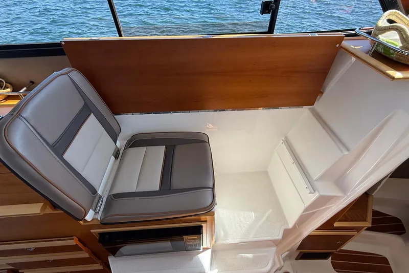 Frisky Yacht Photos Pics 2022 Cutwater C-32 CB interior with cushioned seating and wooden accents, overlooking water.