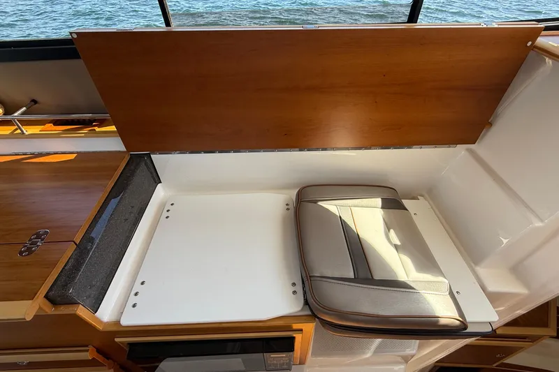 Frisky Yacht Photos Pics 2022 Cutwater C-32 CB interior with foldable seat and wooden paneling.