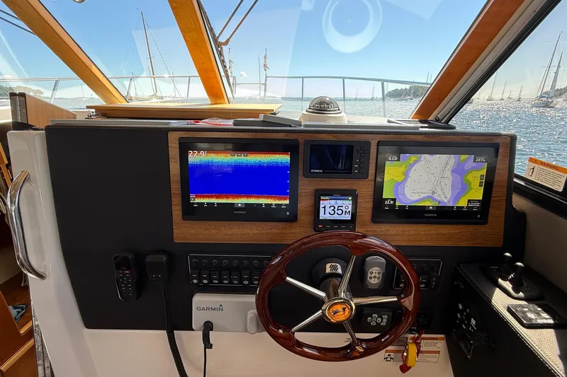 Frisky Yacht Photos Pics 2022 Cutwater C-32 CB helm with navigation screens and steering wheel, overlooking a marina.