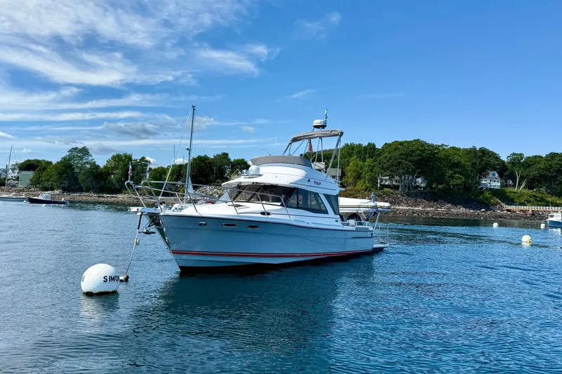 Frisky Yacht Photos Pics 2022 Cutwater C-32 CB boat anchored in scenic coastal waters under a clear blue sky.