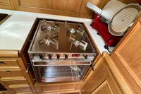 Wood-paneled kitchen with stove and appliances on a 2006 Custom Felci 71 yacht.