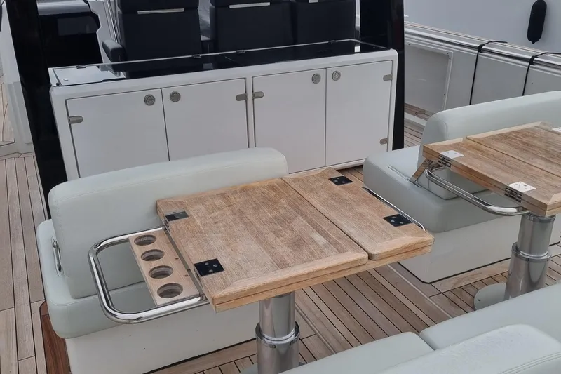 Yacht Photos Pics Luxury seating area on 2019 Fjord 44 Open yacht with wooden tables and cup holders.