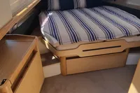Cozy cabin interior of 2019 Fjord 44 Open with striped bedding and wooden furnishings.