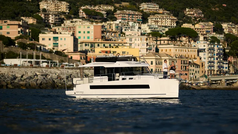  Yacht Photos Pics 2025 Northman 1300 yacht cruising near colorful coastal town buildings.