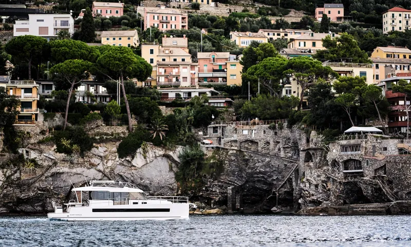  Yacht Photos Pics Yacht Northman 1300 (2025) cruising near scenic coastal village with colorful hillside houses.