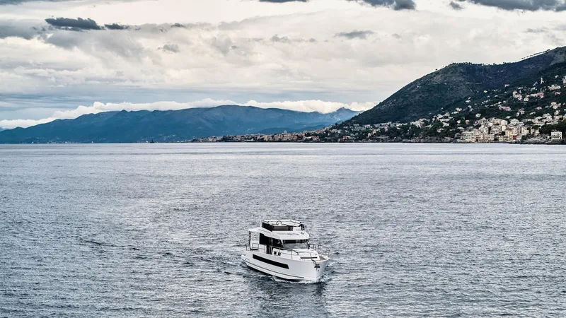  Yacht Photos Pics 2025 Northman 1300 yacht cruising on a scenic coastal waterway with mountainous backdrop.