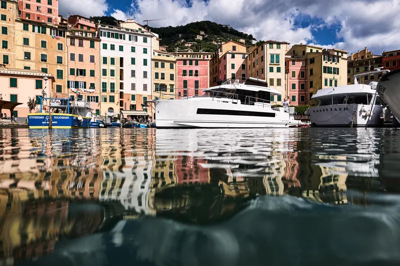  Yacht Photos Pics Colorful waterfront with boats, including a 2025 Northman 1300, reflecting on calm water.