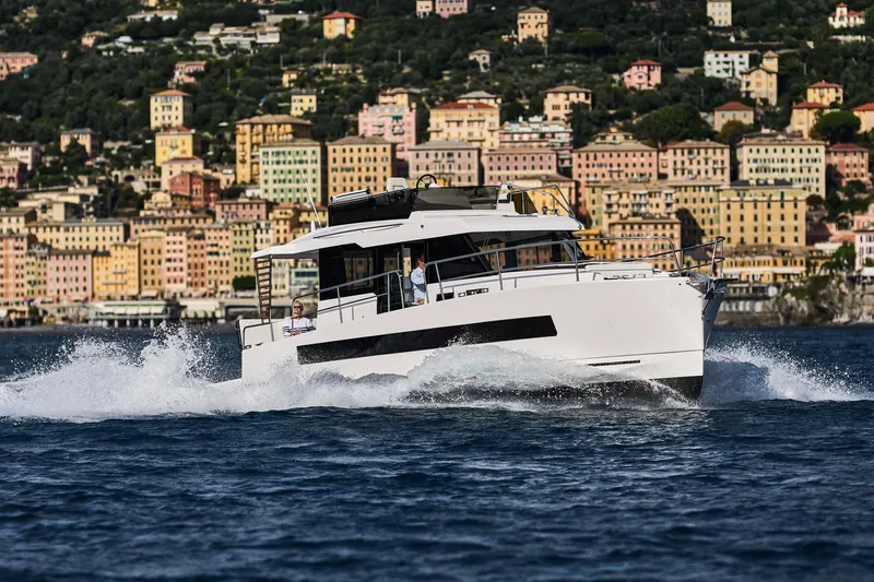  Yacht Photos Pics 2025 Northman 1300 yacht cruising near colorful coastal buildings.