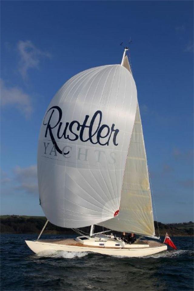 Sailing yacht Rustler 33, 2025 model, with large spinnaker on open water.