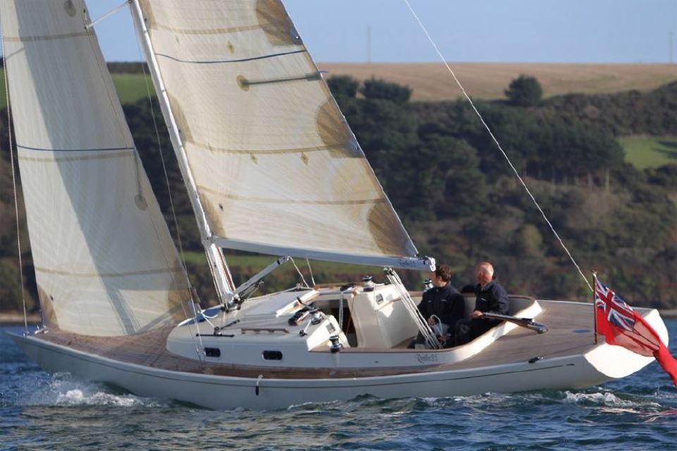 2025 Rustler 33 sailboat navigating coastal waters with two people onboard.